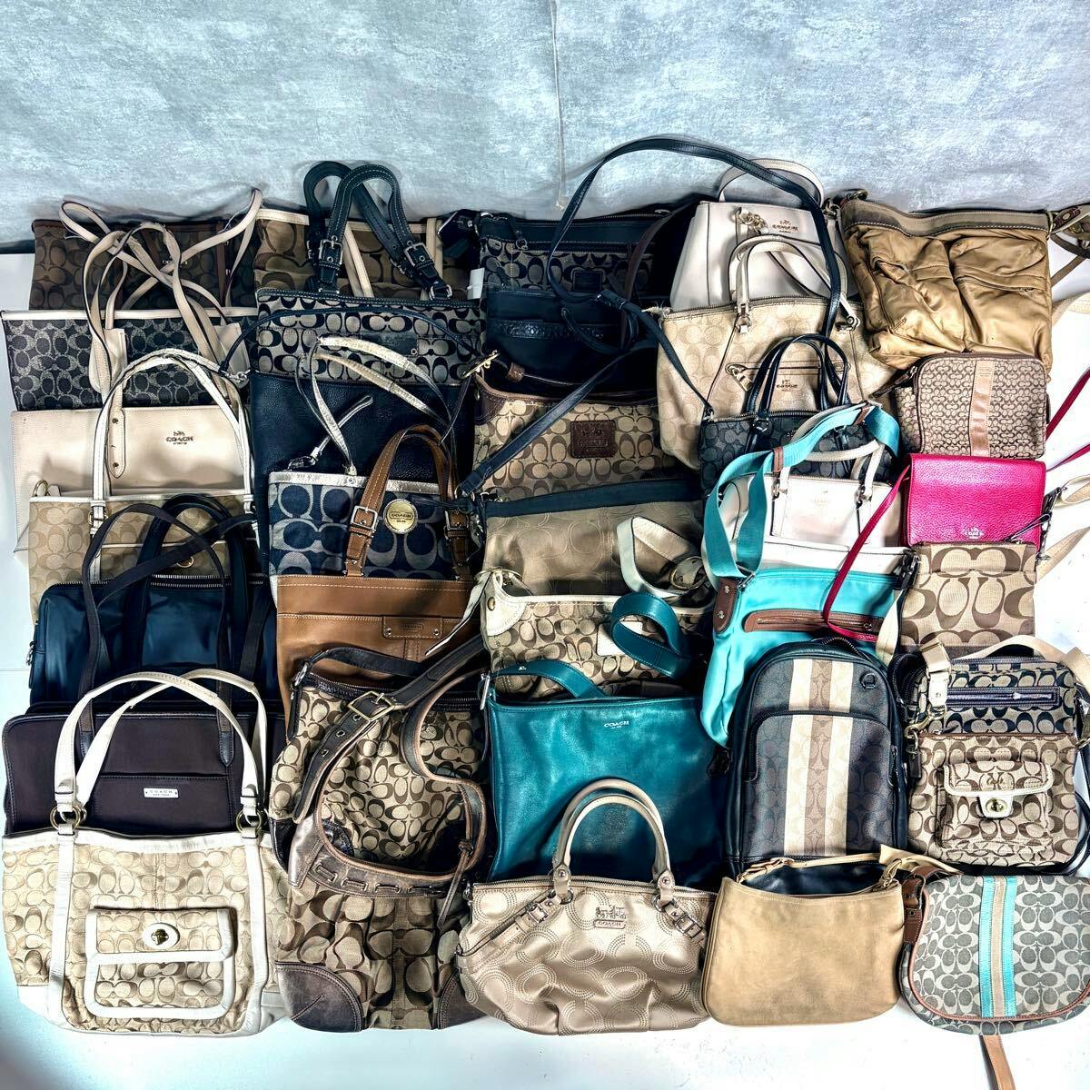 Overhead photo showing a bulk set of Coach shoulder and crossbody bags, many with the signature 'C' canvas pattern, arranged together.