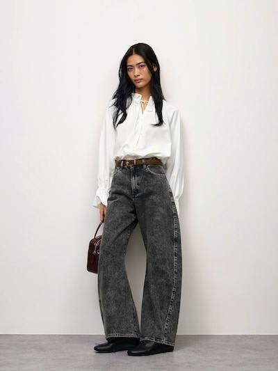 Model wearing dark grey washed wide-leg women's jeans with a white blouse and brown belt.