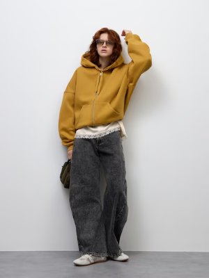 Model wearing the women's 3D barrel jeans in dark gray, styled with a mustard hoodie against a white background.