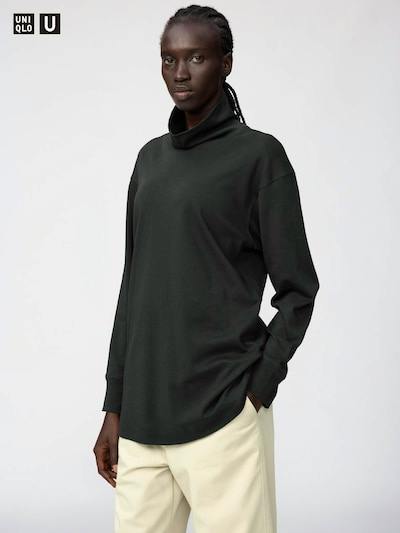 Model wearing a dark mock-neck long-sleeve cotton sweater shown from mid-thigh up against a plain background.