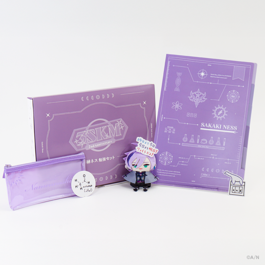 Photograph of the 3SKM 2nd Anniversary study support set showing a purple A4 clear file, a translucent purple pencil case, a round sticker, a purple box, and a small chibi character figure.