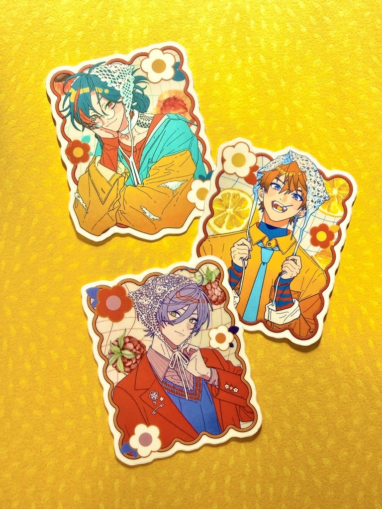 Three illustrated paper stickers from the 3SKM sticker set arranged on a yellow background.