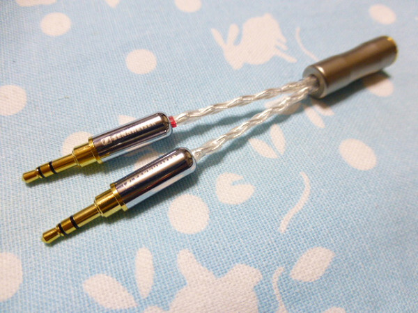 Two gold-plated 3.5mm male plugs on braided silver-coated cable leading to a 4.4mm female connector.