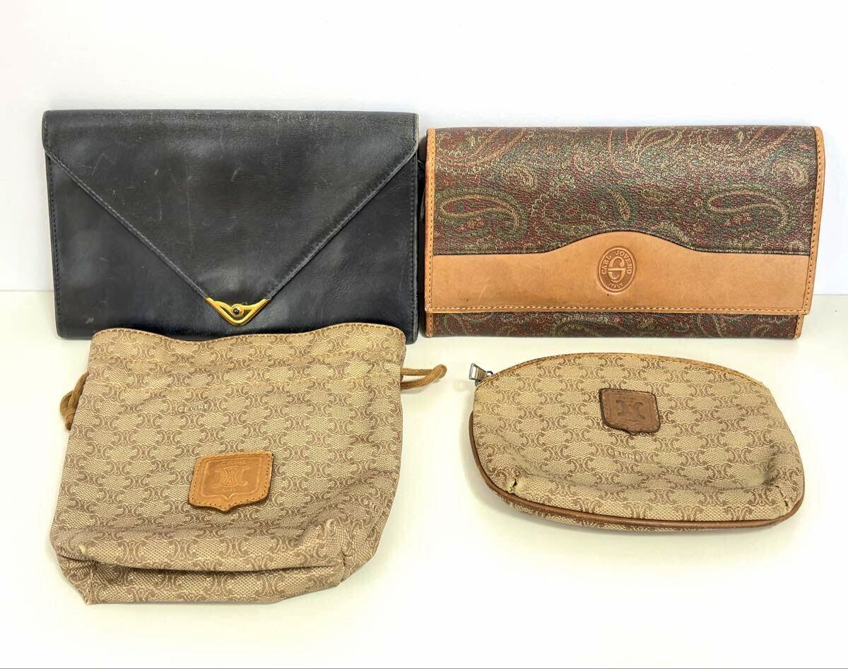 Four items arranged on a white surface: a paisley-pattern long wallet, a black envelope clutch, a beige CELINE monogram drawstring pouch, and a beige monogram zip pouch.