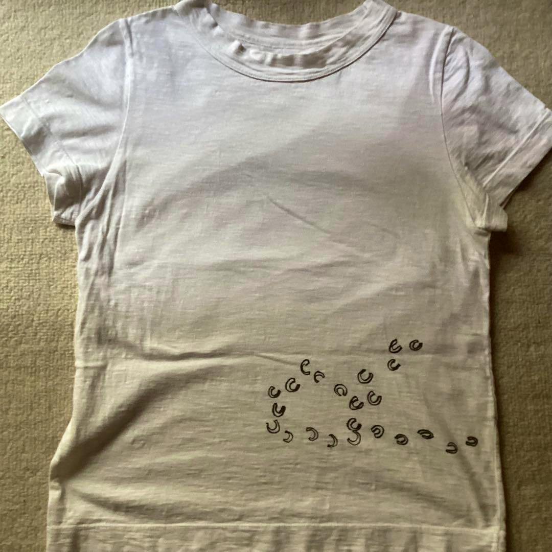 White cotton short-sleeve T-shirt laid flat showing a cluster of black horseshoe-print motifs on the lower front.