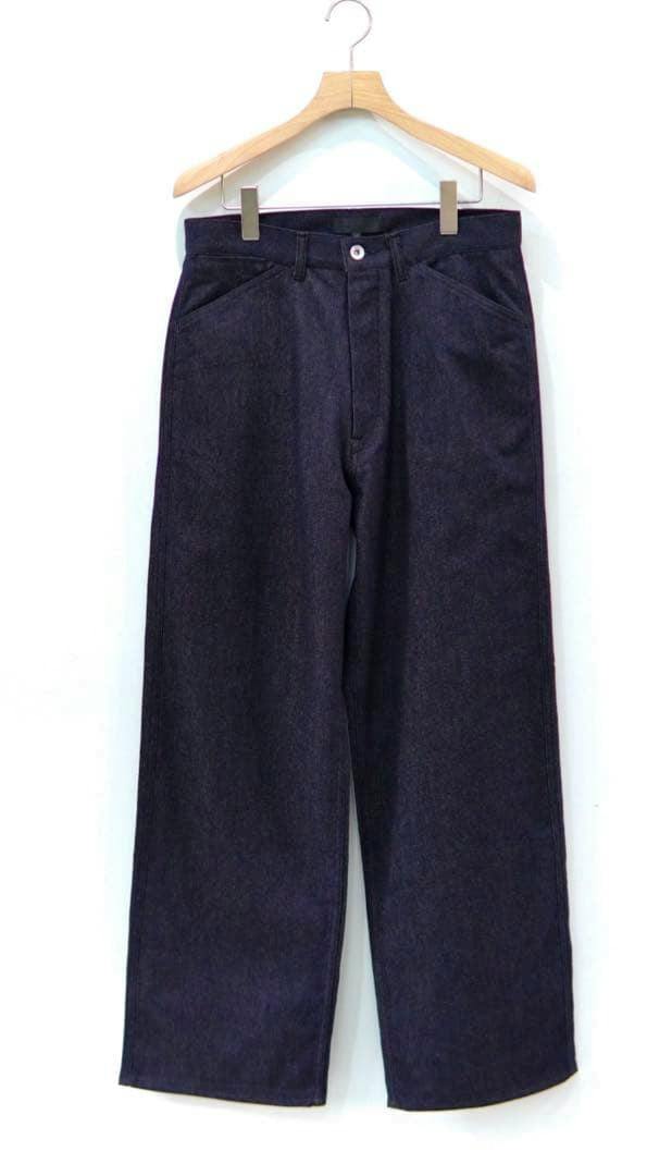 Front view of the men's cashmere cotton denim trousers hanging on a wooden hanger against a white background.