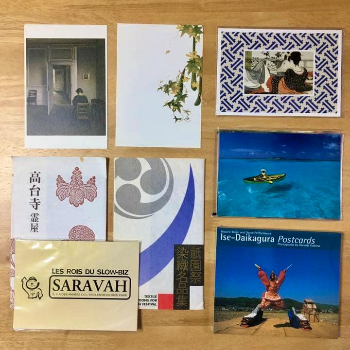 Multiple postcards from the set arranged on a wooden surface showing various designs including landscapes and packaged cards.