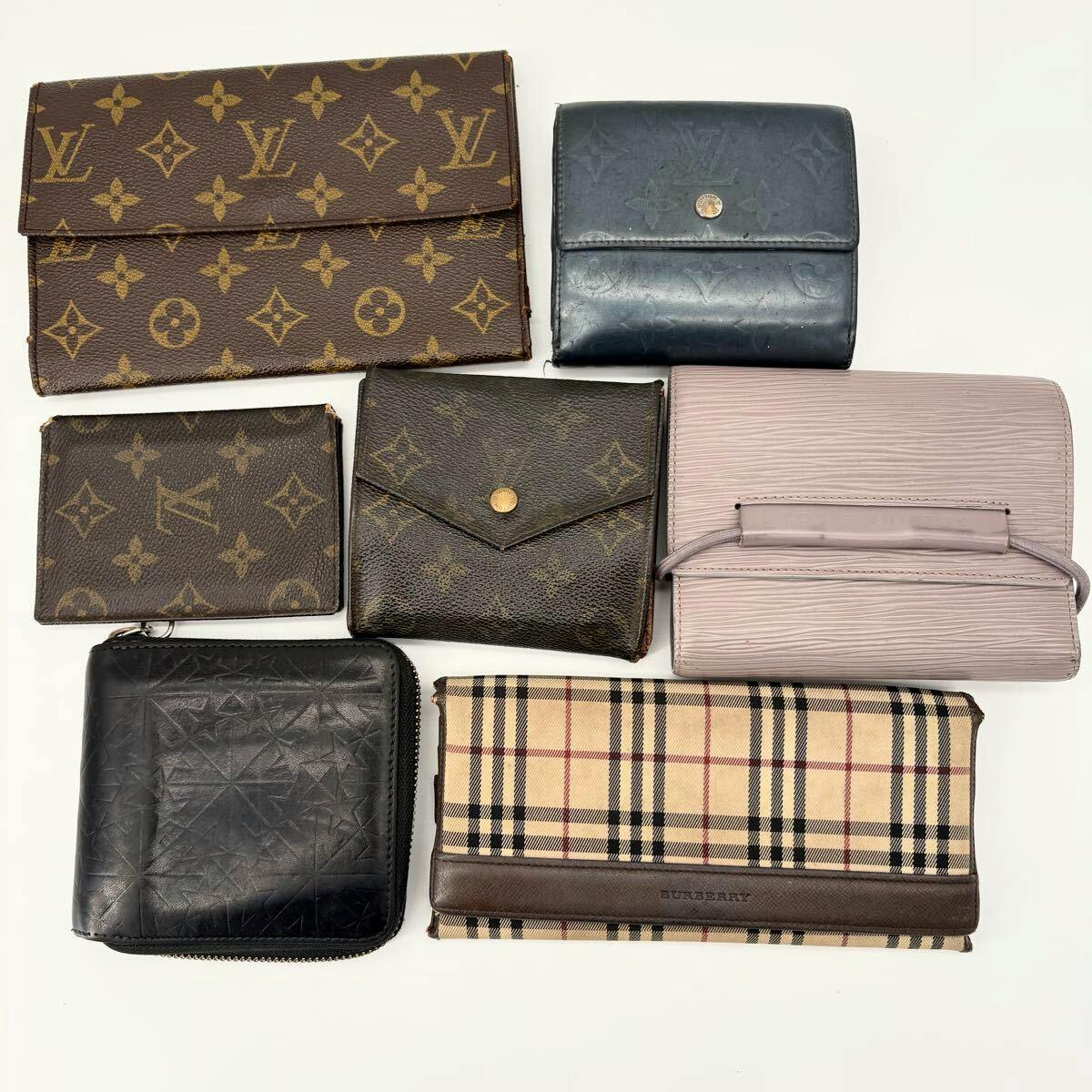 Seven wallets and pass cases, including Louis Vuitton monogram and Burberry check pieces, arranged on a white background.