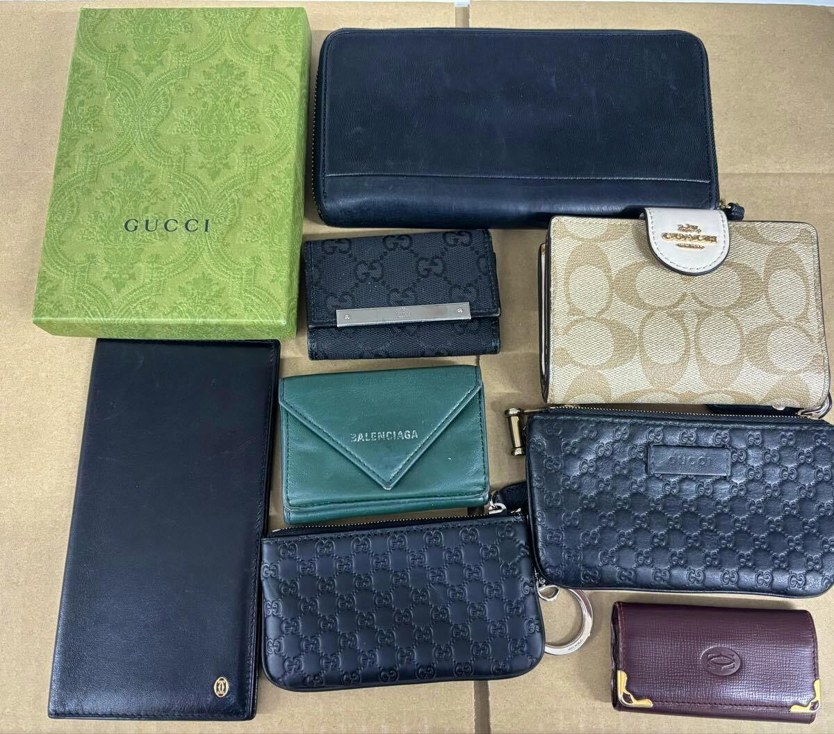 Multiple wallets and small cases arranged on cardboard, including a green box labeled "GUCCI" and several branded wallets visible.