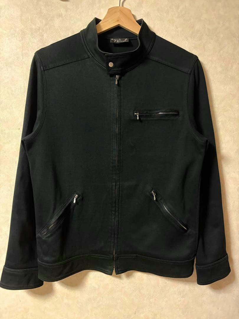 Front view of a black men's cotton jacket with a stand collar and three zippered pockets hanging on a wooden hanger.