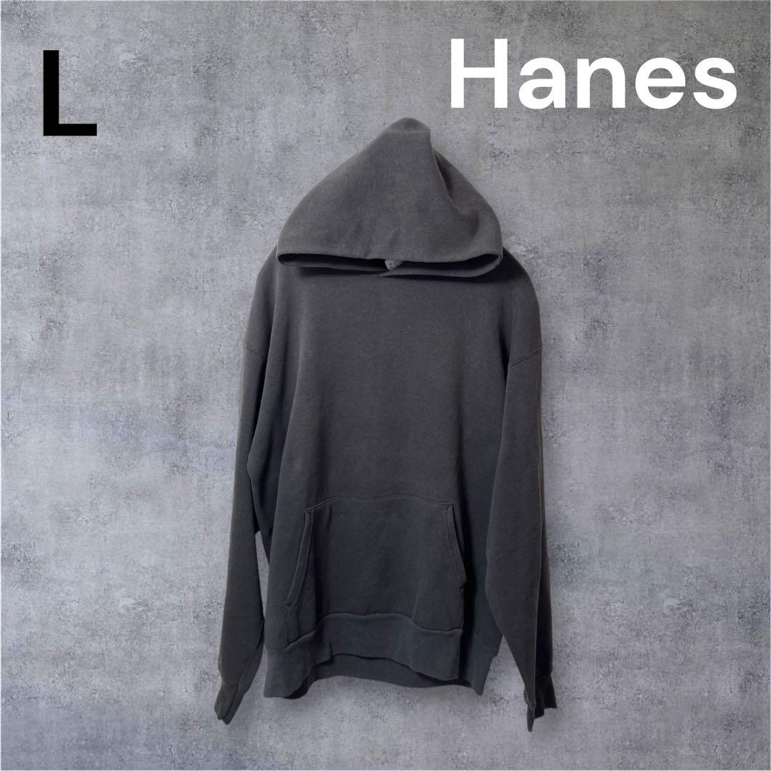 Black Hanes hooded sweatshirt hanging against a textured gray wall, shown from the back.