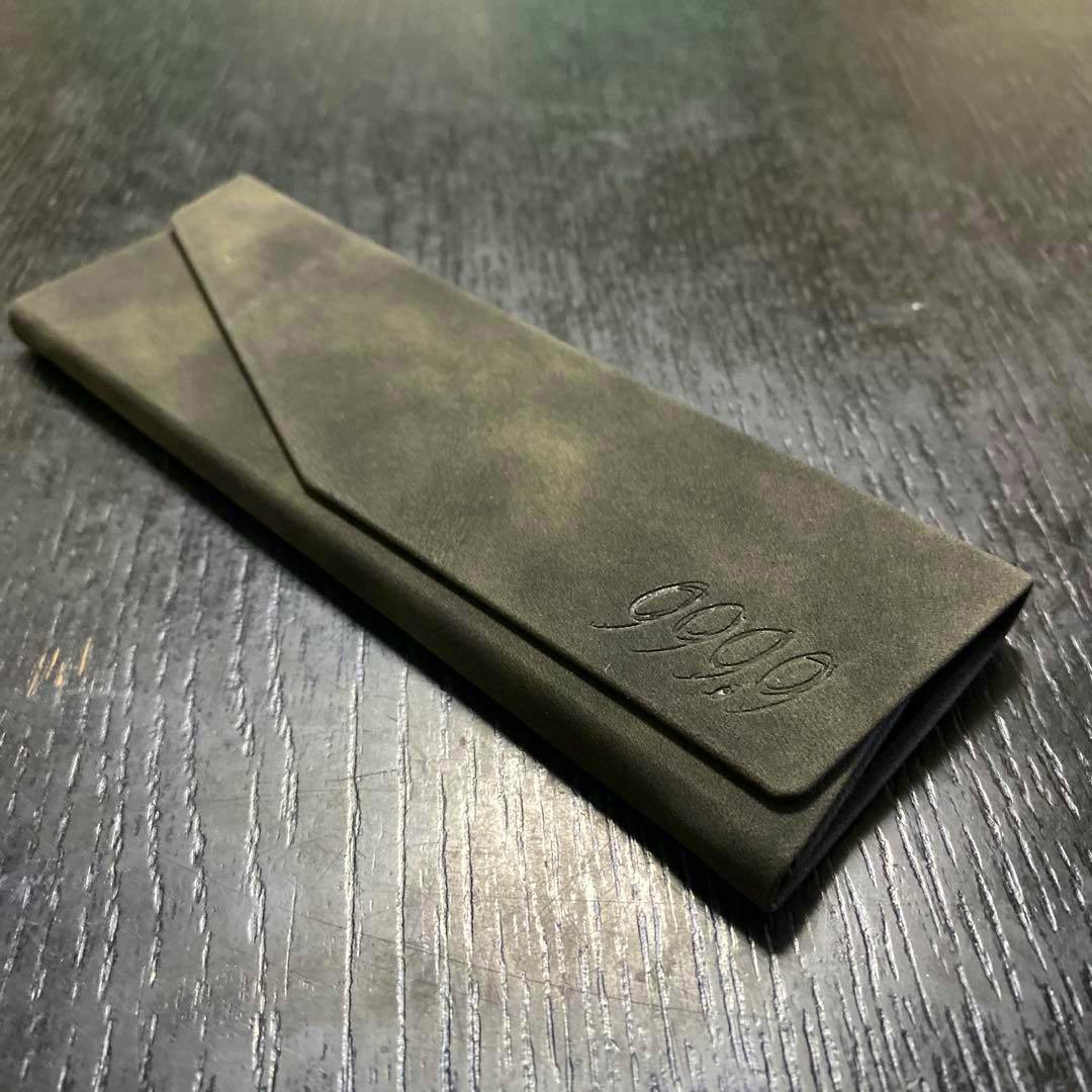 Folded 999.9 folding eyeglasses case placed closed on a dark wooden surface.