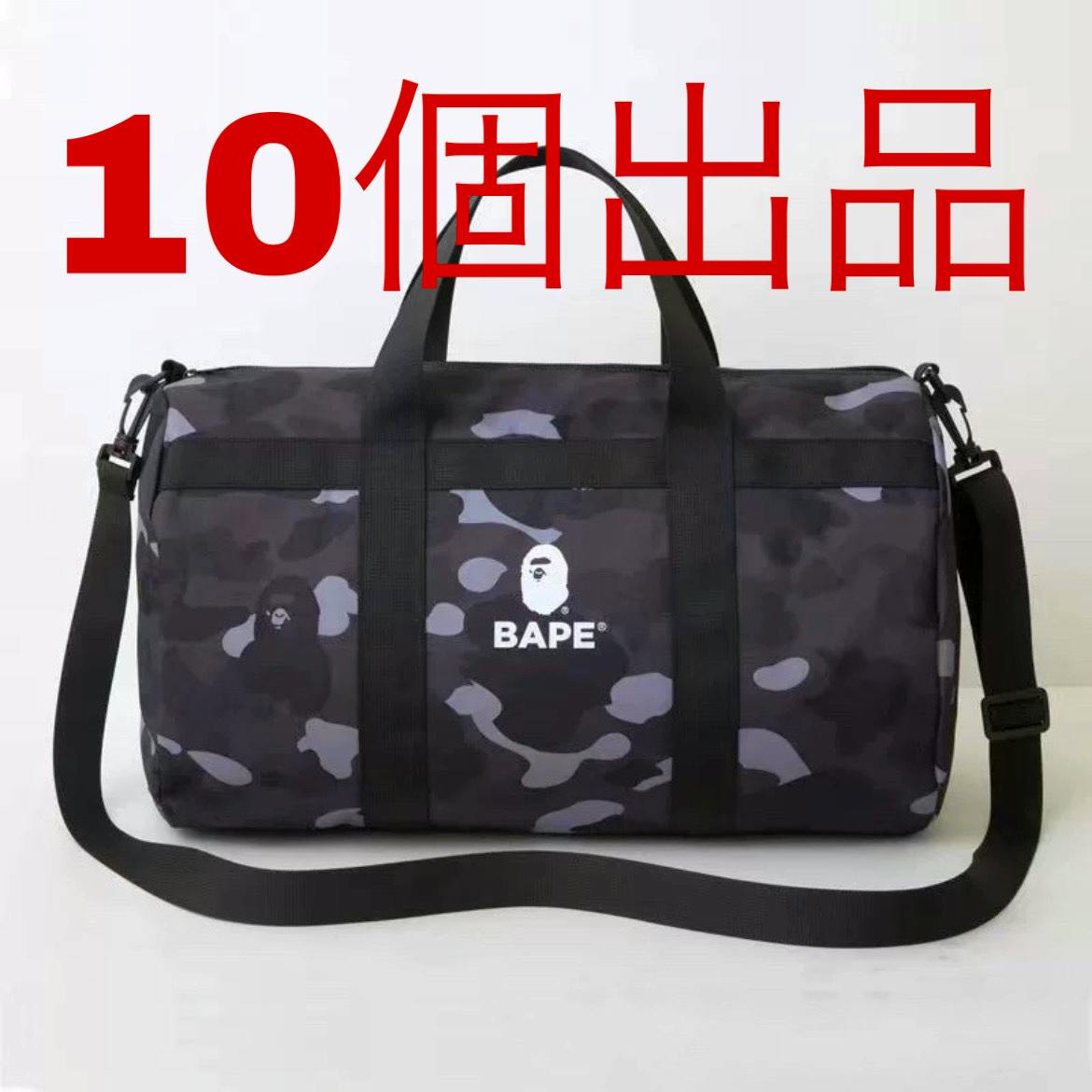 Black camouflage canvas duffle bag by BAPE with black handles, a shoulder strap, and a white BAPE logo on a white background, with large red Japanese text overlay.