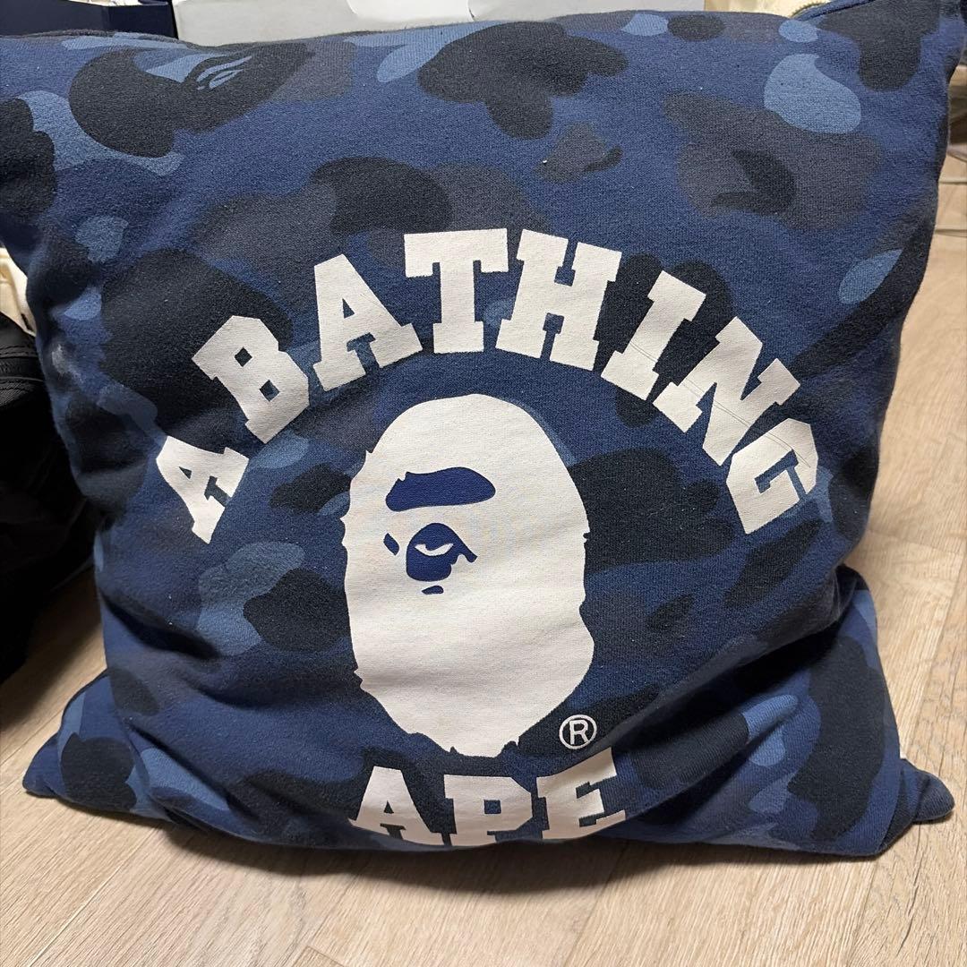 Blue camouflage A BATHING APE cotton cushion cover showing the white ape head logo and 'A BATHING APE' text on the front.