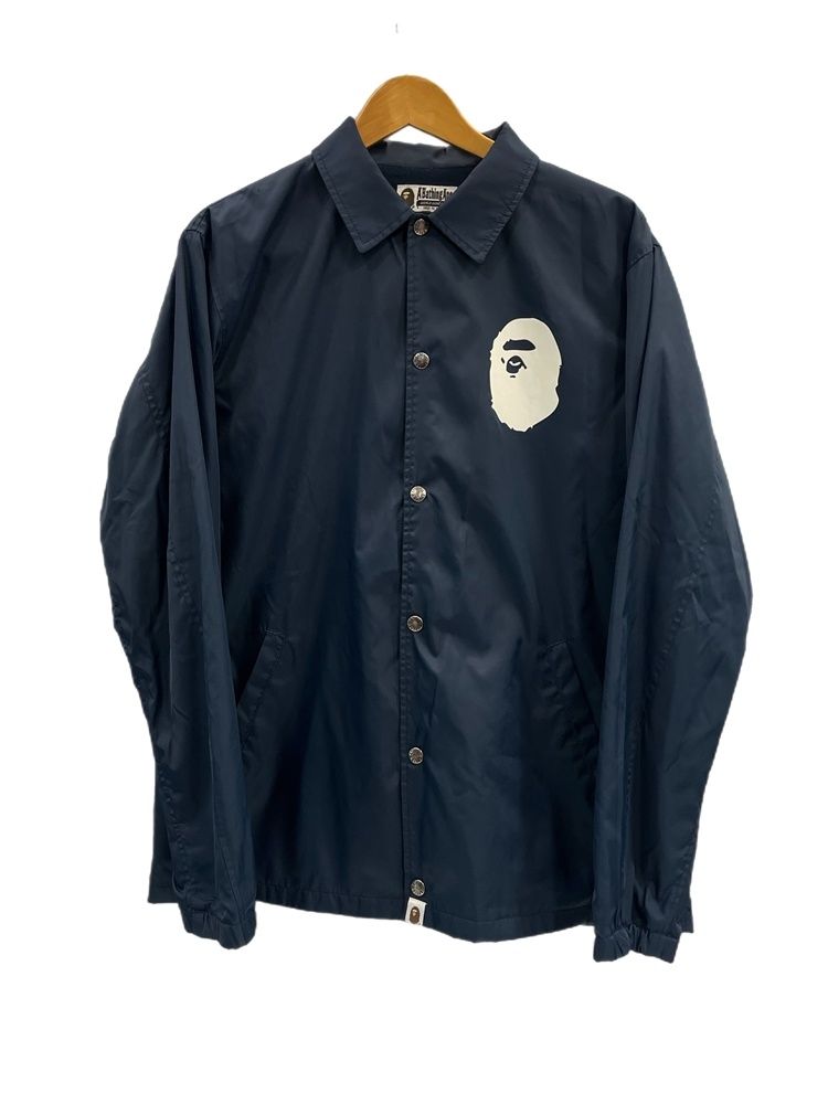 Navy A BATHING APE nylon coach jacket with a white ape head logo hanging on a wooden hanger.