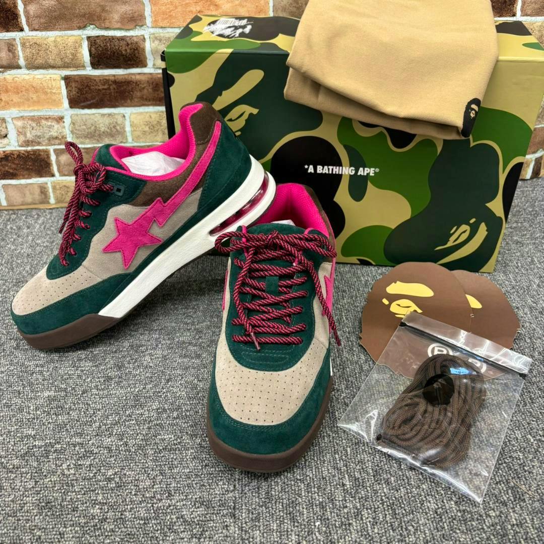 A pair of BATHING APE Road Sta #1 sneakers with pink star logo and green/beige upper displayed with the shoebox, spare laces, and dust bag.