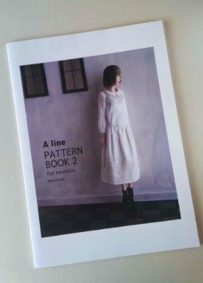 Front cover of the photo book 'A line PATTERN BOOK 2 for momoko' showing a model wearing a white dress against a pale wall.