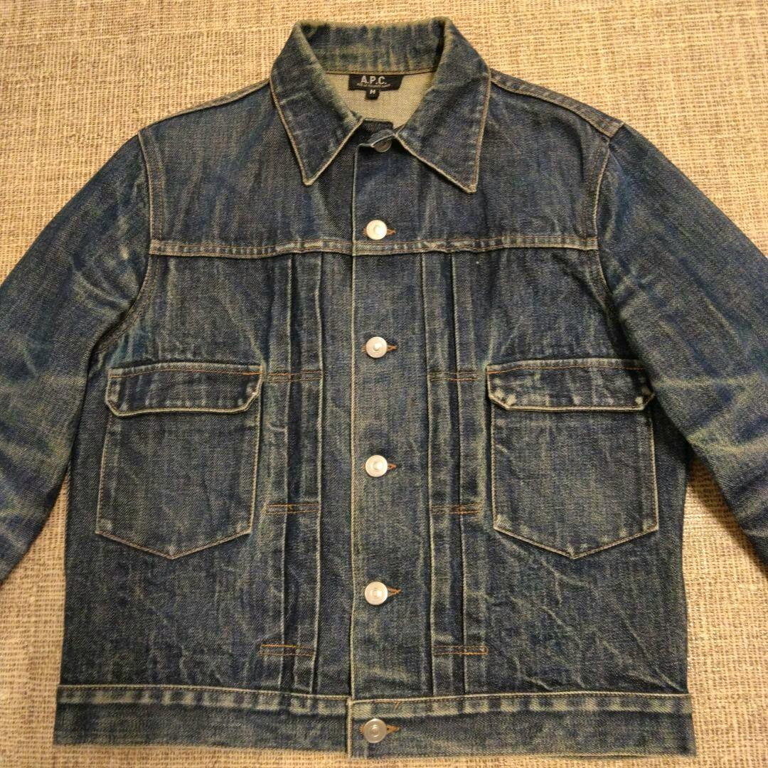 Front view of a men's A.P.C. denim jacket laid flat on a textured surface.