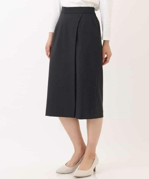 Front view of a black knee-length wrap pencil skirt worn by a model with a white top and beige heels.