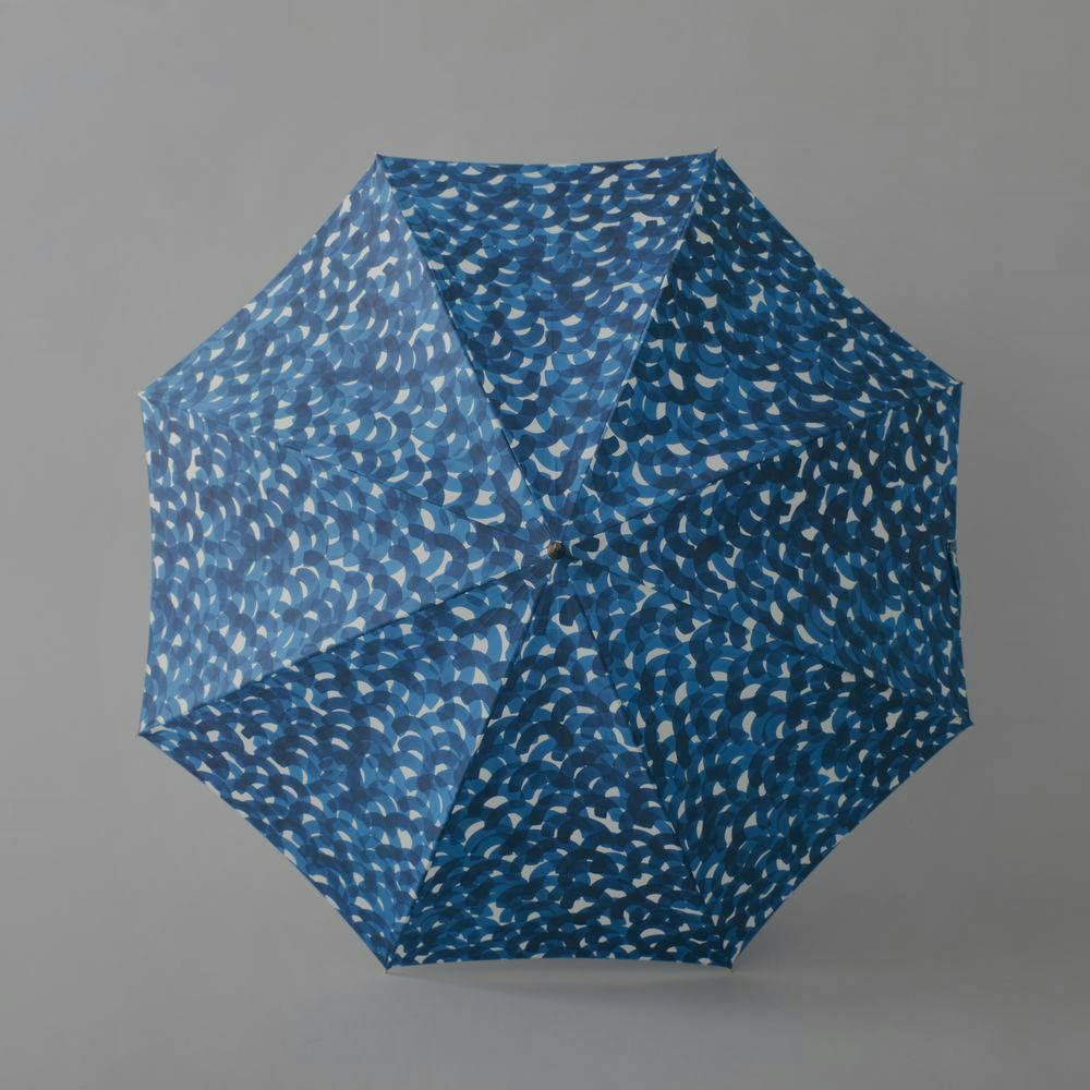 Opened blue umbrella with a repeating wave-like pattern shown from above on a plain grey background.