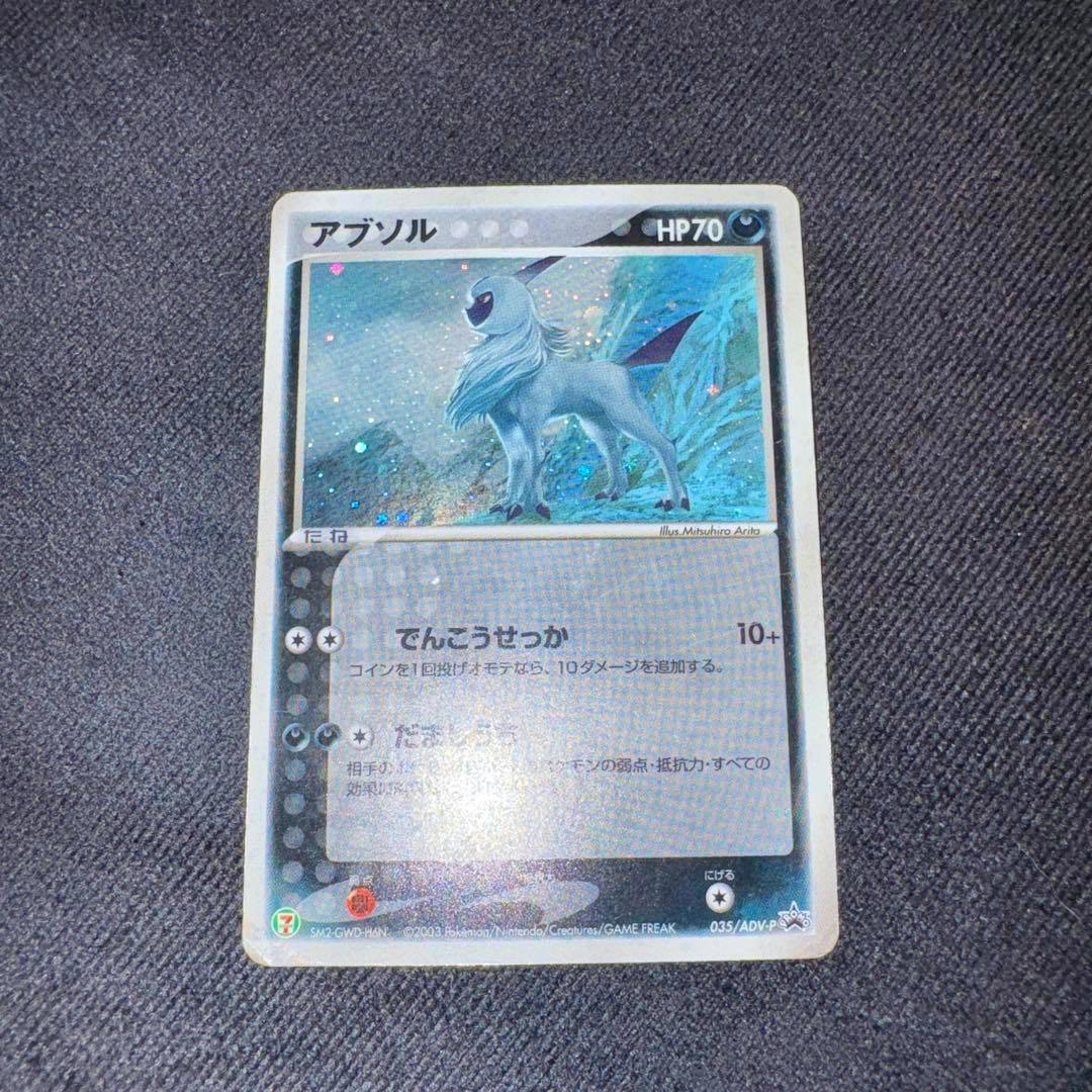 Photo of the Absol promo trading card (035/ADV-P) showing the full card face centered on a dark textured background.