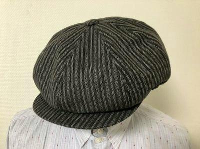 A striped cotton casquette hat displayed on a mannequin torso.