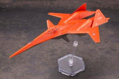 Orange ADF-01 aircraft figure from the ACE COMBAT series displayed on a clear plastic stand against a gray background.