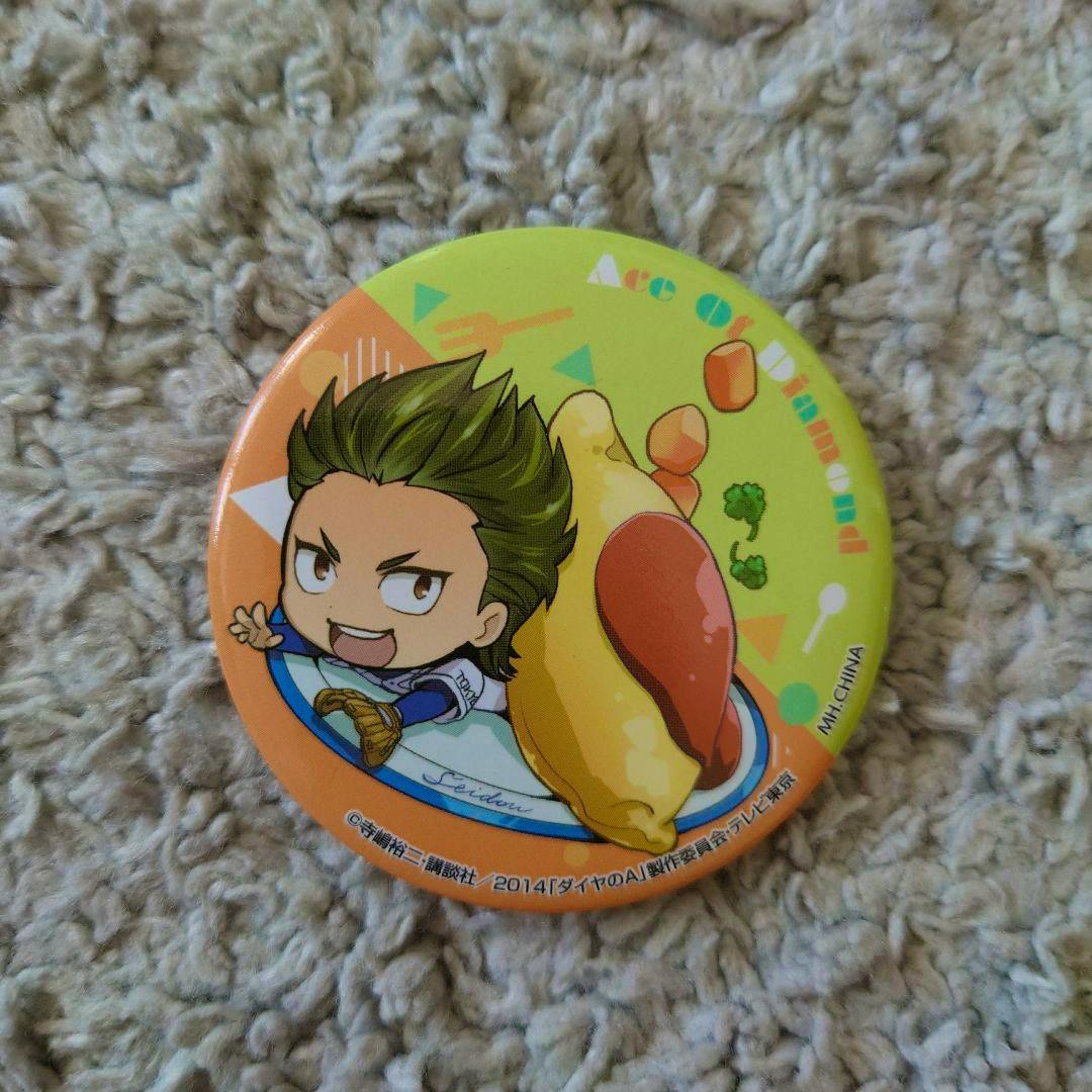 Front of a round can badge showing chibi artwork of 倉持洋一 on a green and orange background.