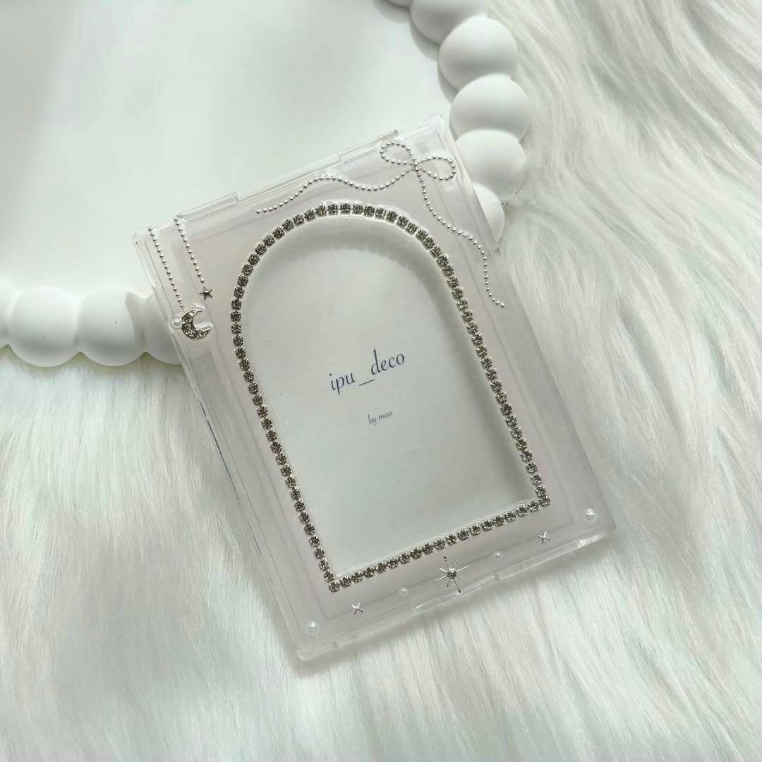 Clear acrylic card case decorated with rhinestones and a small crescent charm placed on a white faux-fur background.