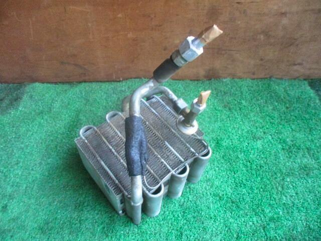 Photograph of the evaporator unit with metal fins and attached tubing placed on a green surface.
