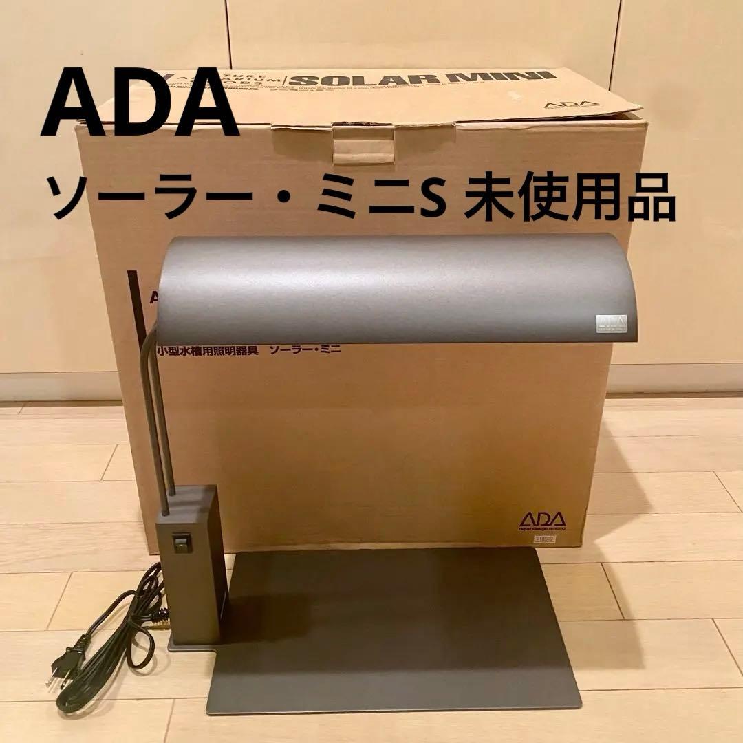 ADA Solar Mini S aquarium lamp assembled on a metal base with its cardboard box behind it.