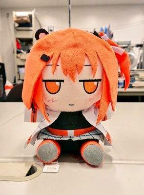 Seated 足立レイ ずもも plush toy on a table.