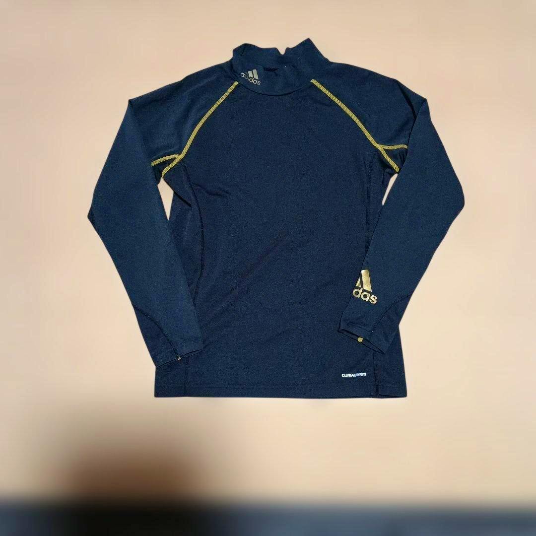 Flat-lay photo of the black kids adidas ClimaWarm high-neck long-sleeve top showing gold contrast stitching and an adidas logo.