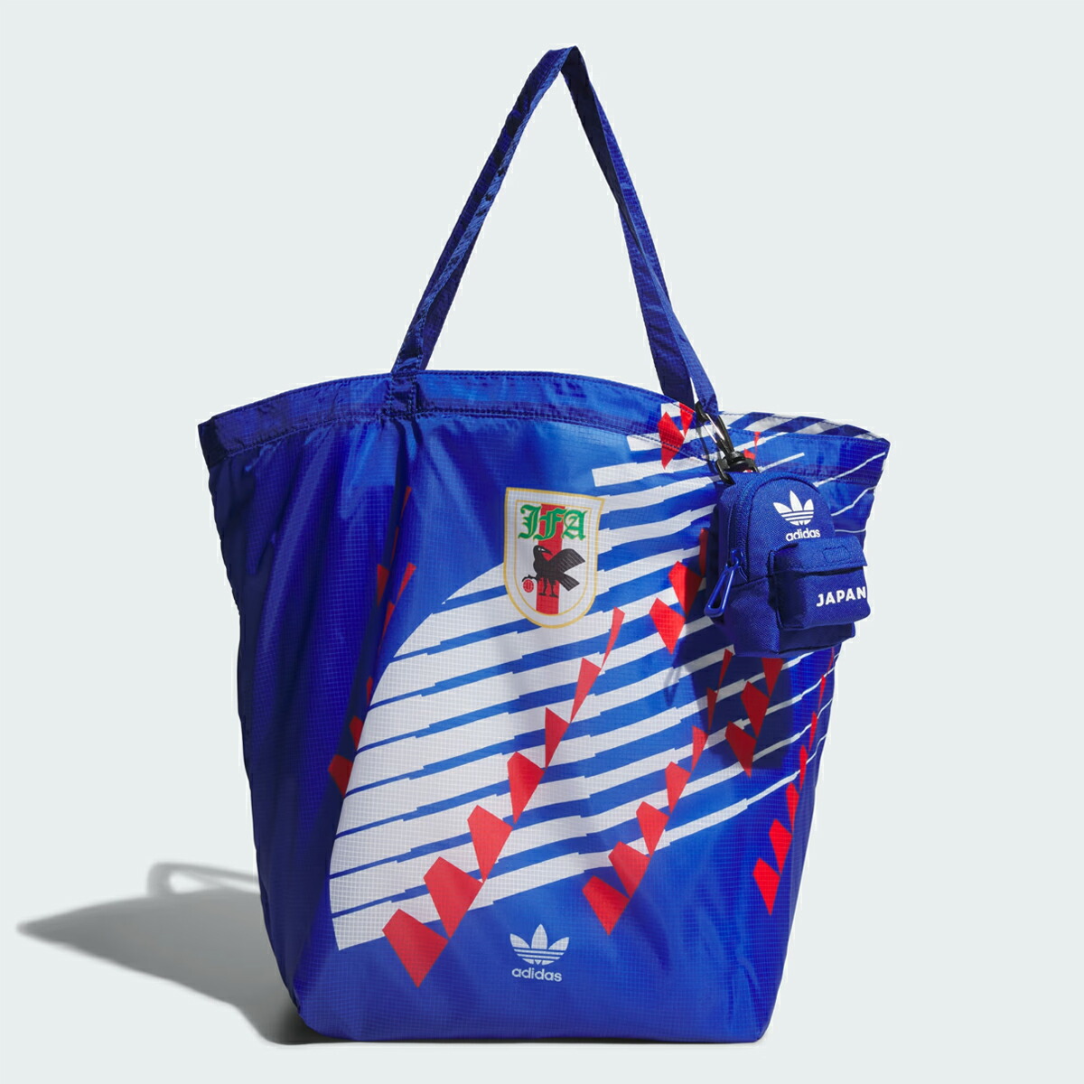 A blue adidas JAPAN packable tote bag with white and red graphic pattern and a small attached pouch.