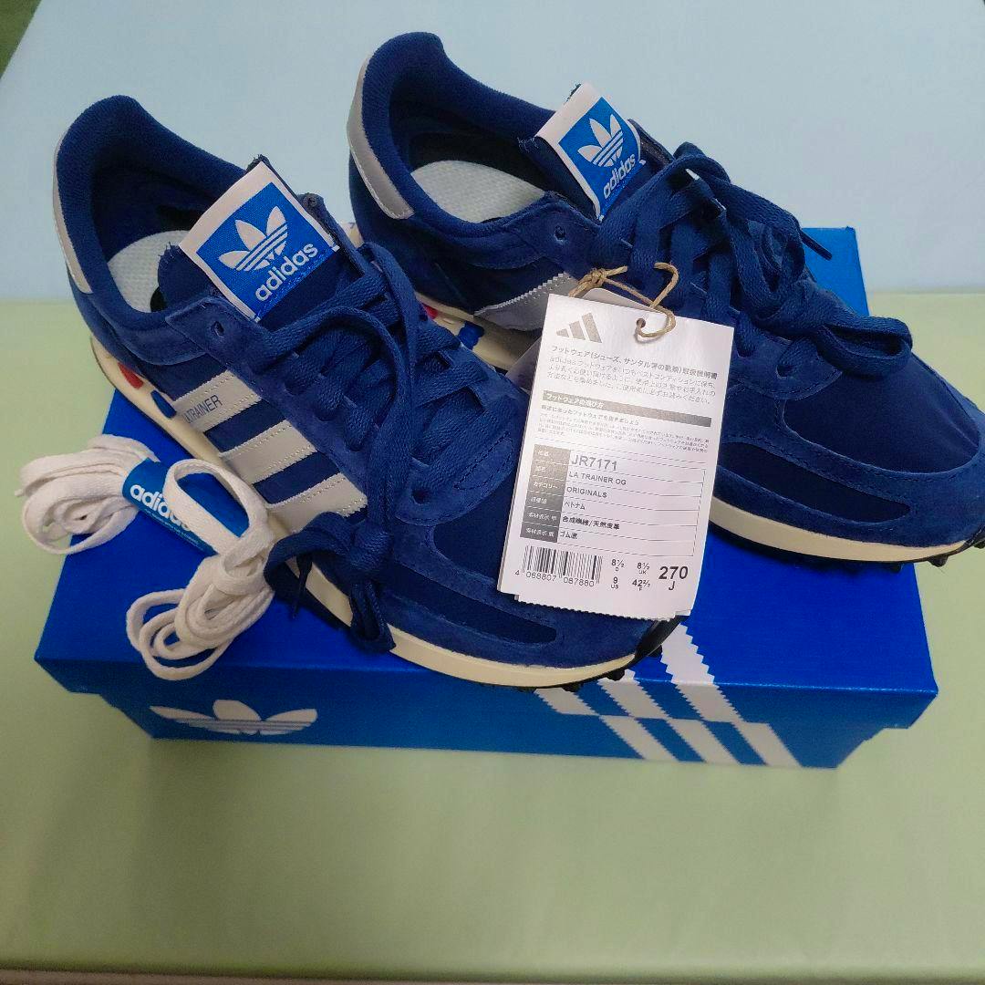 Pair of blue adidas LA TRAINER OG JR7171 shoes with tag on a blue adidas shoebox.