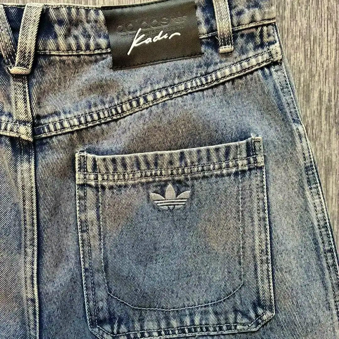 Close-up of the back pocket and waistband of the adidas Skateboarding X KADER Acid Wash Pants showing a trefoil logo and a Kader leather patch.