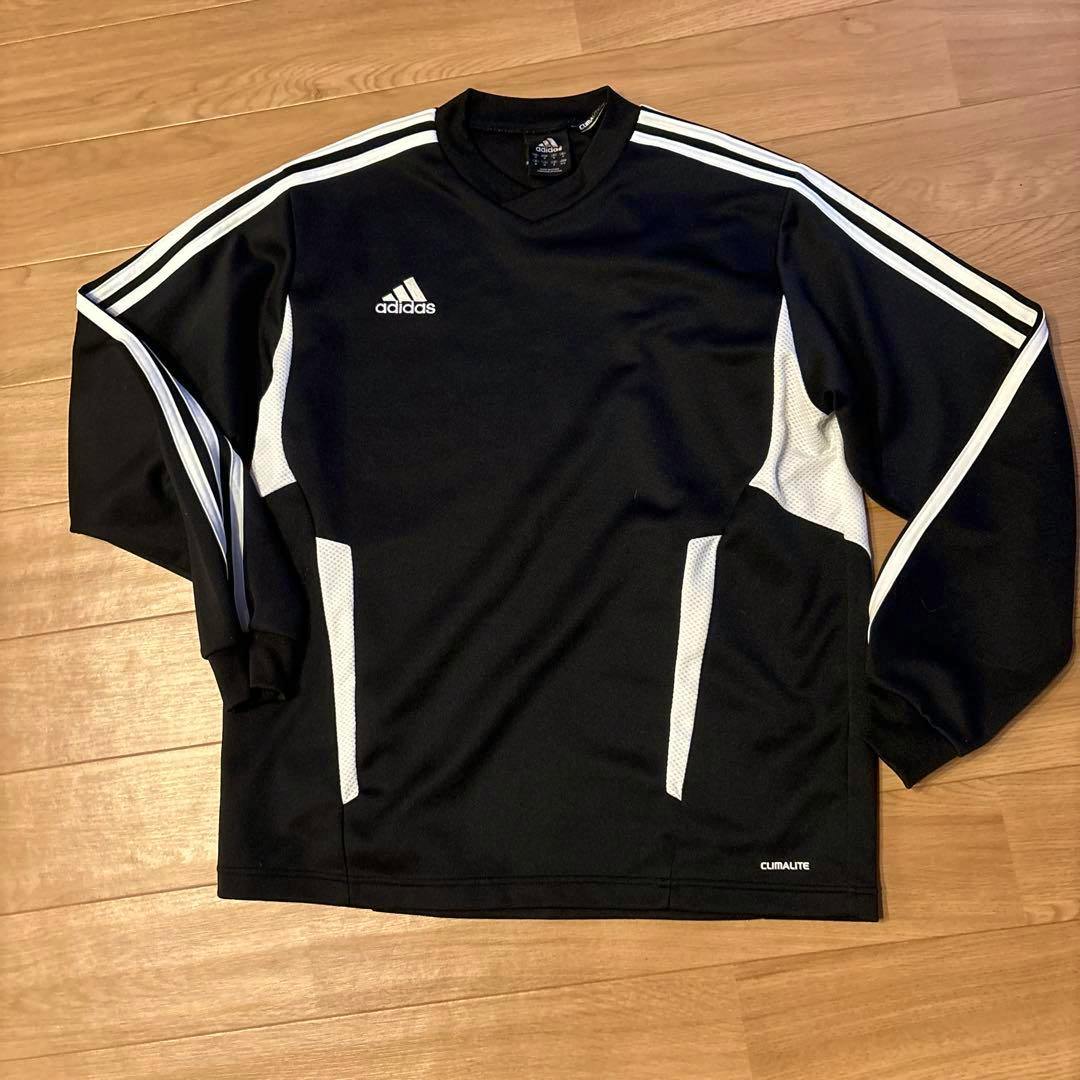 Black adidas long-sleeve soccer jersey (size M) with white shoulder stripes, white mesh side panels, and adidas logo laid flat on a wooden floor.