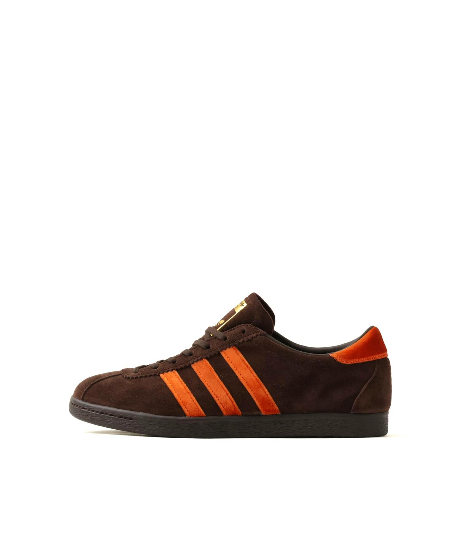 Side view of the adidas TOBACCO atmos "KOYO" brown suede sneaker with orange three stripes and an orange heel.