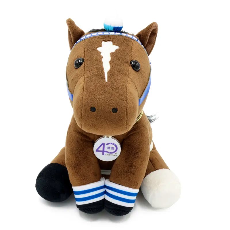 Front view of a brown plush toy horse wearing a blue headband, striped leg bands, and a round "40" anniversary tag.