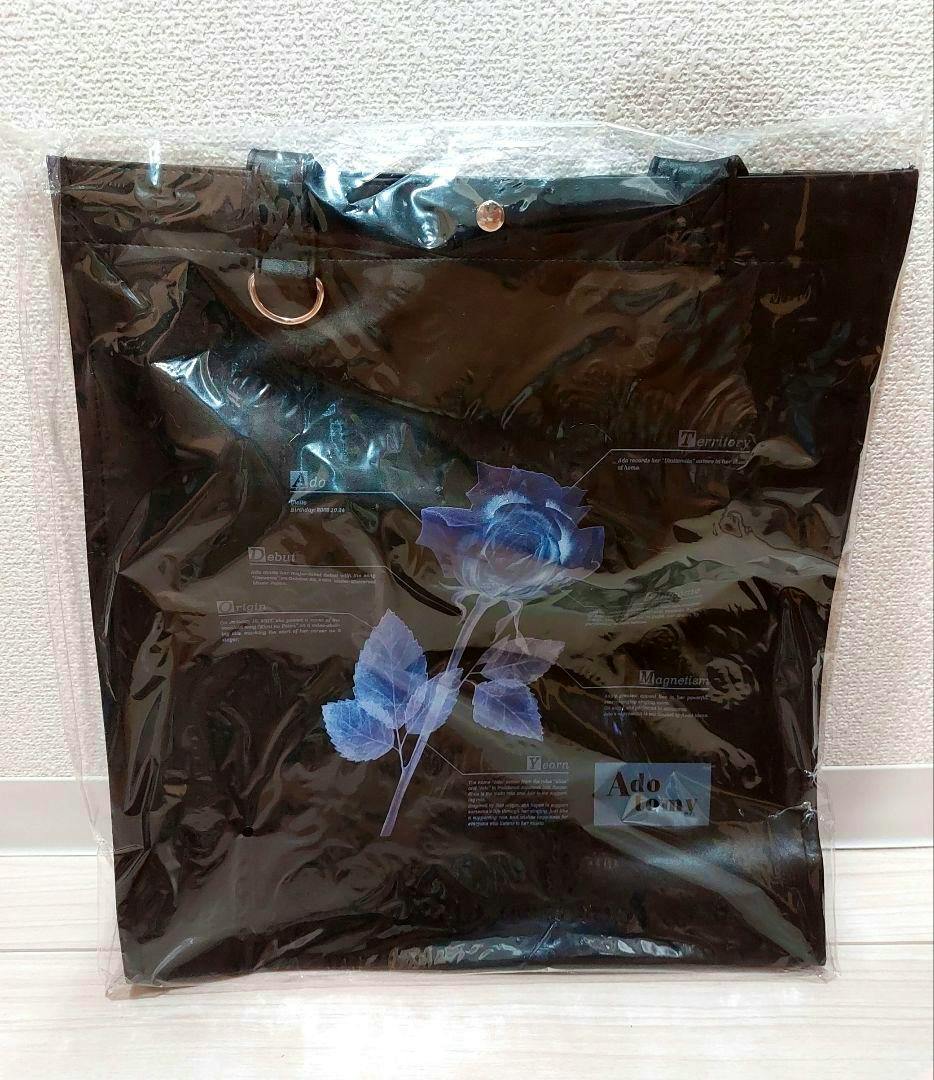 Black synthetic leather tote bag (Ado 5th Adotommy) with a blue rose print, shown sealed in clear plastic packaging.