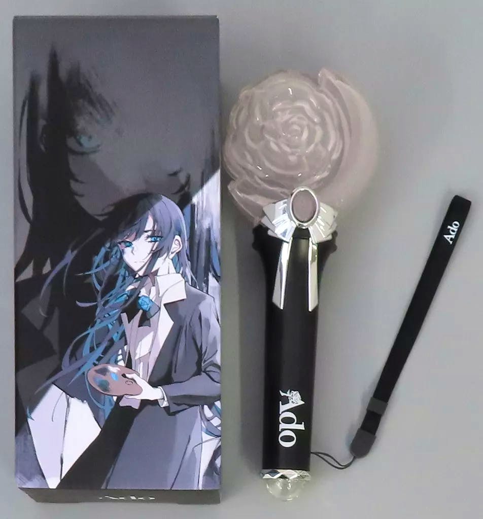 Black Ado penlight with a rose-shaped light head, wrist strap, and an illustrated box beside it.