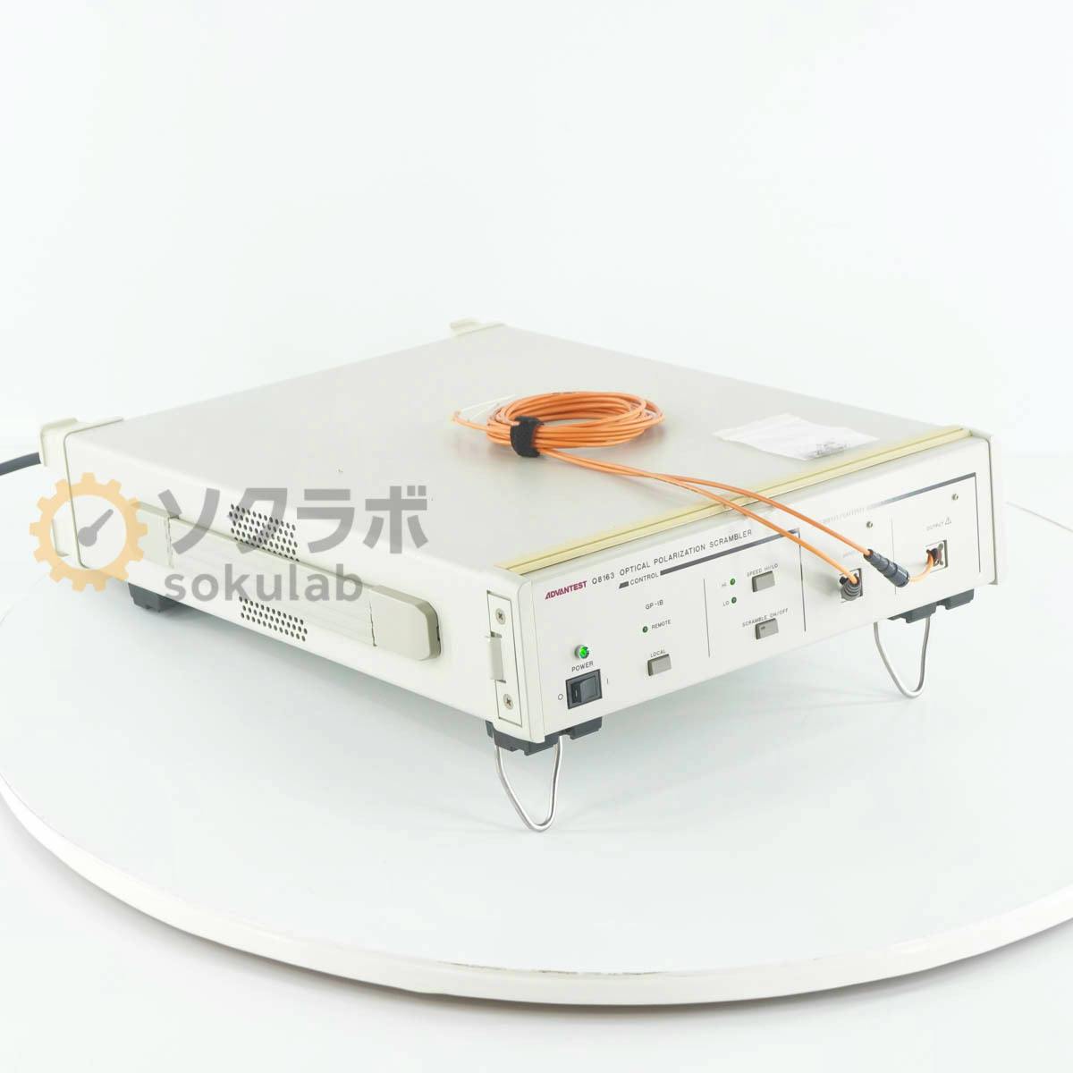 Advantest Q8163 optical polarization scrambler unit with orange fiber cables on a white background.