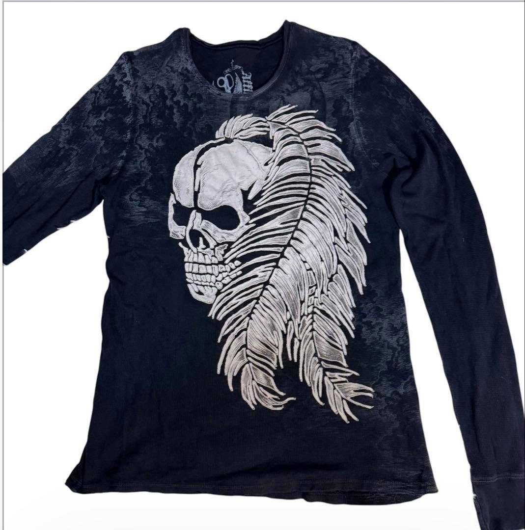 Black men's long-sleeve T-shirt laid flat on a white background, showing a large skull with feather graphic on the front.