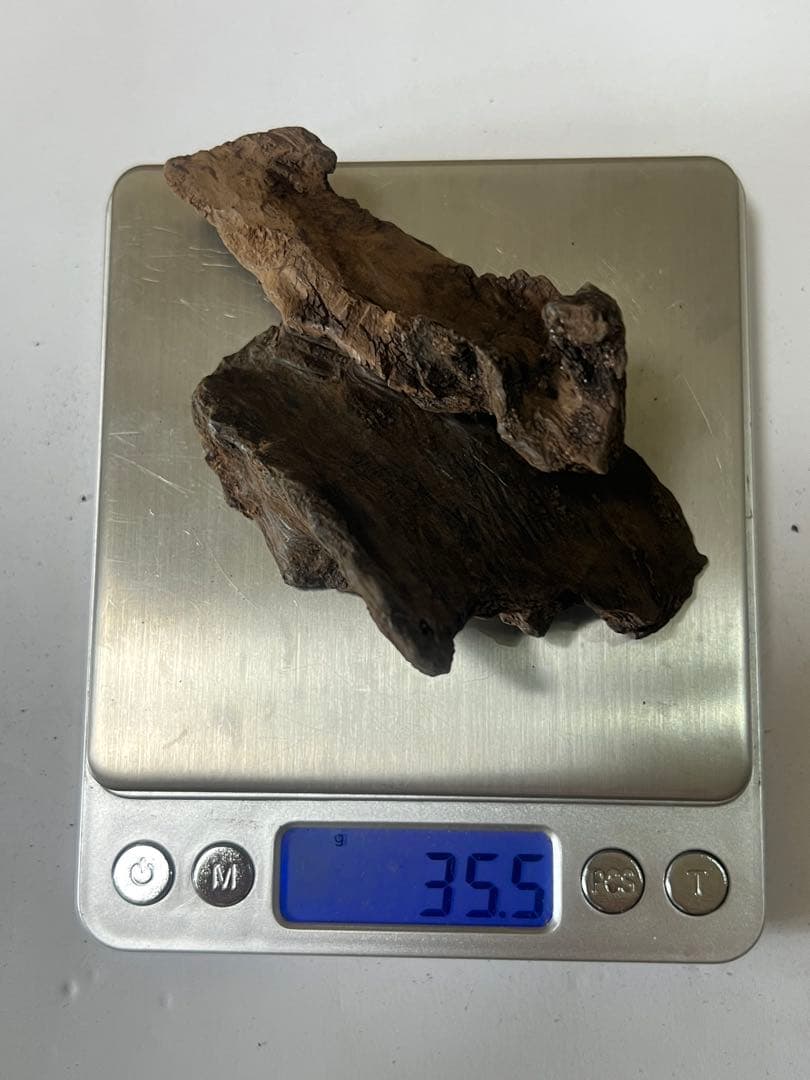 Two pieces of agarwood (incense) placed on a digital scale reading 35.5 g.
