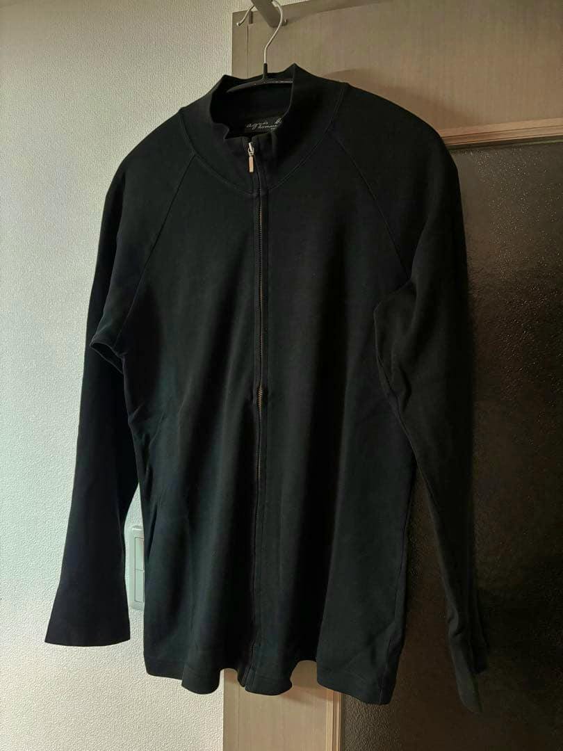 Black Agnes b homme zip-front sweatshirt hanging on a hanger against a wall.