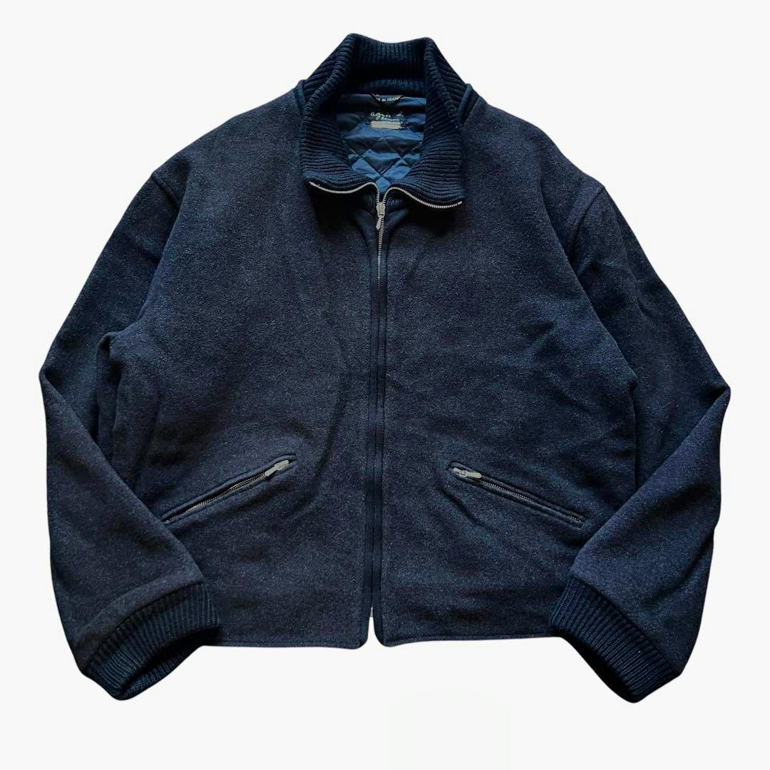 Flat-lay photo of a men's black wool zip-up blouson jacket with ribbed collar and zippered pockets.