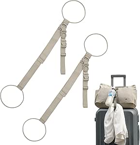 Two khaki adjustable suitcase belts with circular rings, shown next to a rolling suitcase with a bag secured on top.
