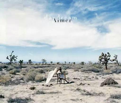 Front cover of Aimer's "daydream" CD showing a desert landscape with a small seated figure under a cloudy sky and the album title.