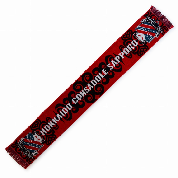 A red towel-style cotton scarf with fringe, Ainu-style patterns, and white HOKKAIDO CONSADOLE SAPPORO text.