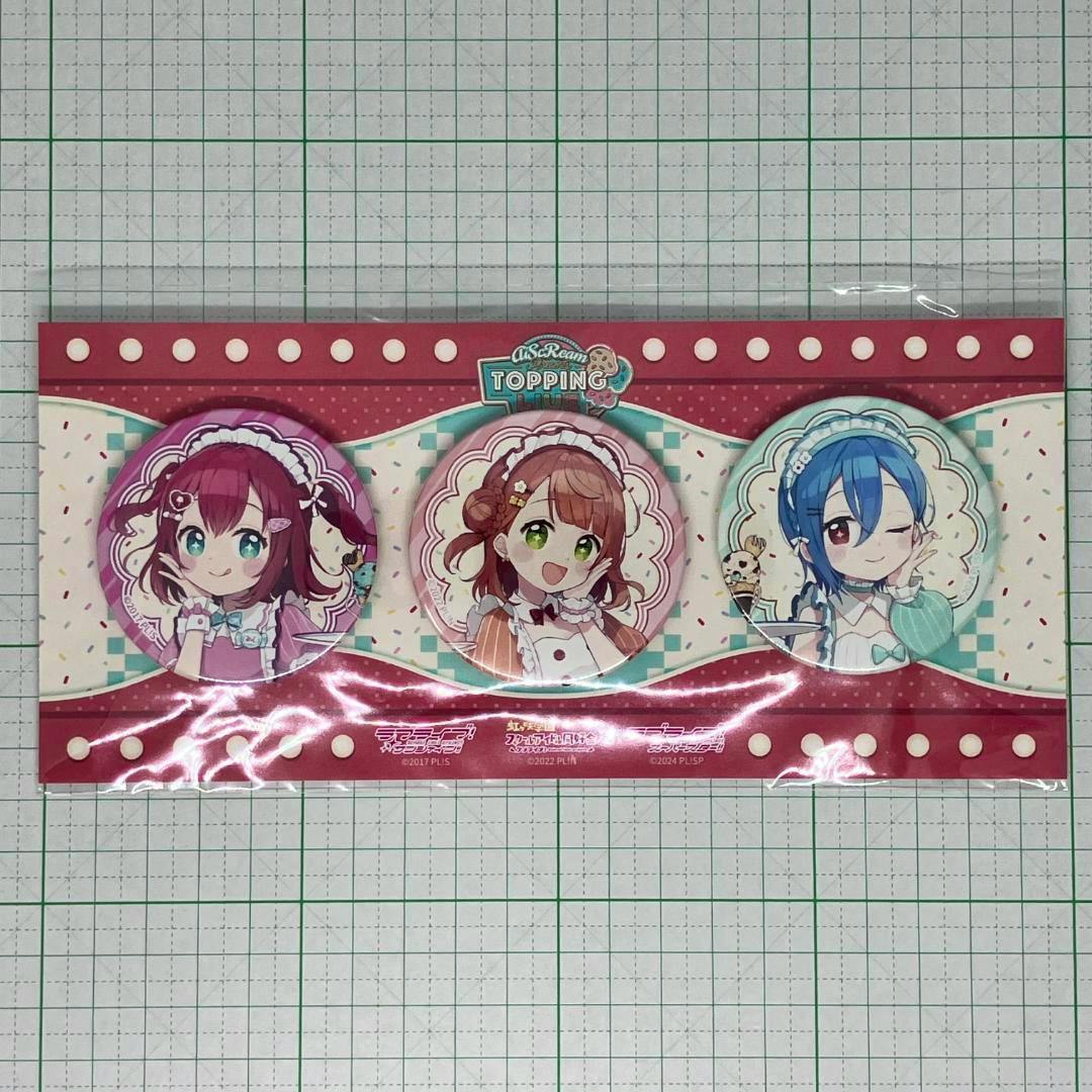 Three round can badges (AiScReam "TOPPING LIVE" set) showing illustrated characters displayed on a red decorative backing inside plastic packaging.